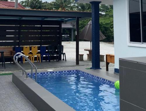 a swimming pool in front of a house with a patio at D' Lembah Pool Homestay Sekinchan in Sekincan