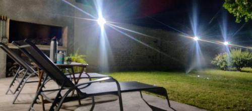 two chairs and a table in a backyard at night at La casa de Flor in San Martín