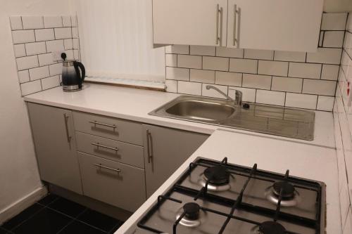 a kitchen with a stove top oven next to a sink at Goodison Accommodation in Liverpool