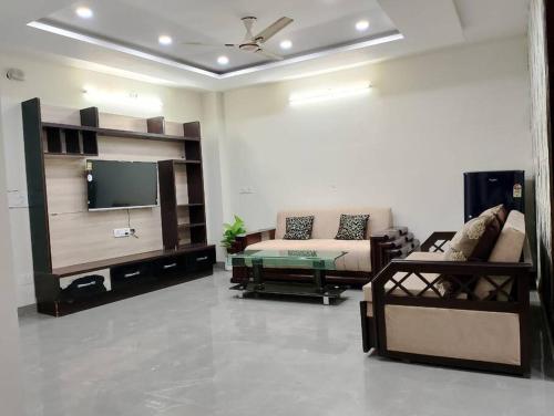 ein Wohnzimmer mit einem Sofa und einem Flachbild-TV in der Unterkunft Homlee-Vintage Green 2BHK with Terrace & fort View in Neu-Delhi