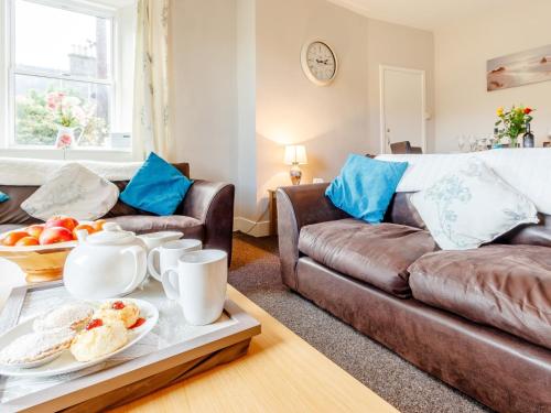 a living room with a couch and a table with food at 3 Bed in Edinburgh 79550 in Kirknewton