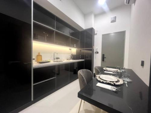 een keuken met zwarte kasten en een zwarte tafel bij Novo KL, Astonishing Unique Executive Suite in Kuala Lumpur