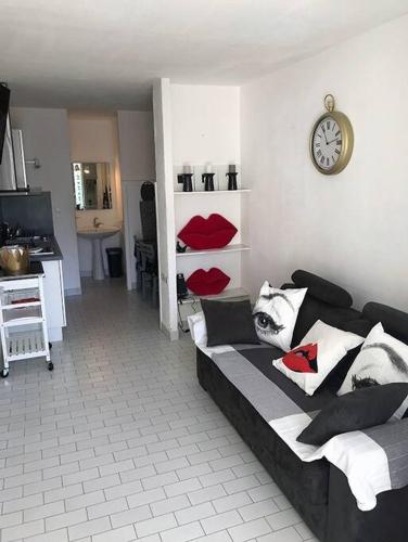 un salon avec un canapé et une horloge au mur dans l'établissement Studio 411, Port Nature 4 au village naturiste, au Cap d'Agde