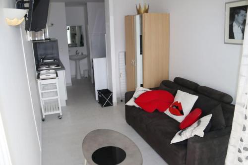 un salon avec un canapé noir avec des coussins rouges dans l'établissement Studio 411, Port Nature 4 au village naturiste, au Cap d'Agde
