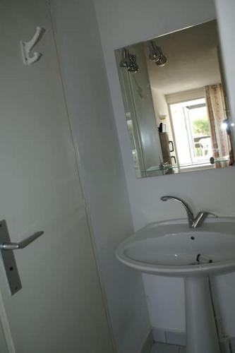 une salle de bain blanche avec un lavabo et un miroir dans l'établissement Studio 411, Port Nature 4 au village naturiste, au Cap d'Agde
