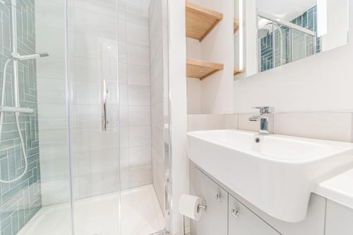 La salle de bains blanche est pourvue d'un lavabo et d'une douche. dans l'établissement Central Kendal Georgian Home with private courtyard & free parking, à Kendal