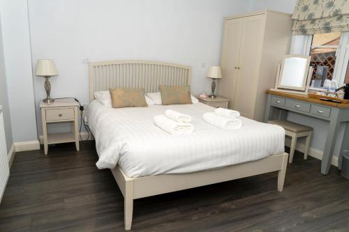 a bedroom with a white bed with towels on it at The Finch Hatton Arms in Sleaford