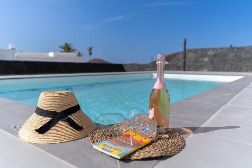 eine Flasche Wein und ein Hut neben einem Pool in der Unterkunft VV Villa Secretos de Yaiza 3 by HH - private pool & BBQ in Yaiza