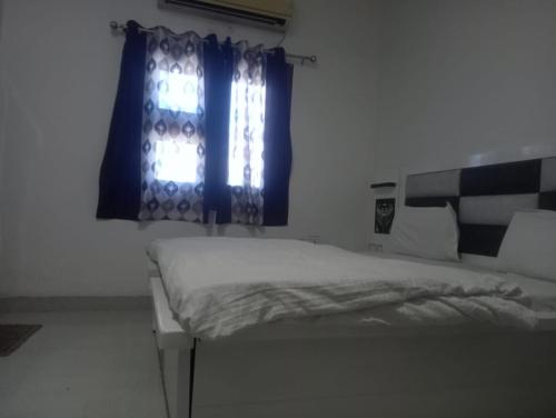 een slaapkamer met een bed en een raam met blauwe gordijnen bij Gurjeet Hotel by Naavagat in Amritsar