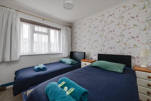 a bedroom with two beds and a window at Coastal Haven in Felpham