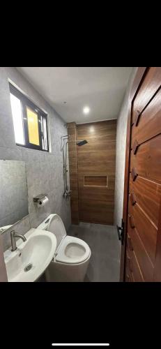 a bathroom with a toilet and a sink and a door at Cavite’s Cozy Villa in Imus
