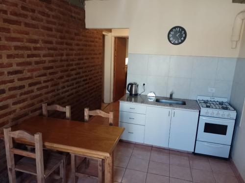 a kitchen with a table and a stove and a sink at Departamentos Haiti in Bahía Blanca