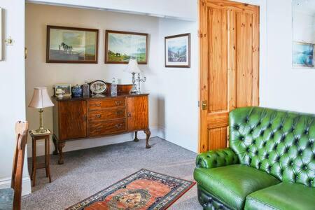 a living room with a green couch and a wooden cabinet at Host & Stay - Freshwater River View in Dunoon