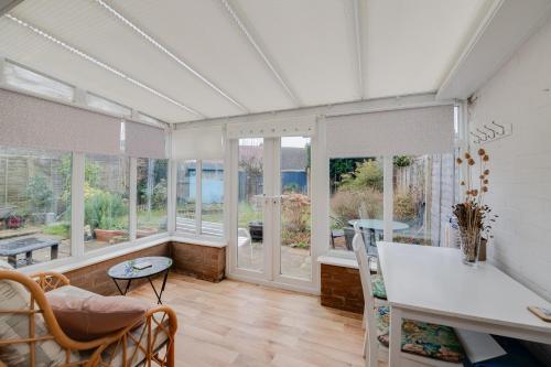 a living room with windows and a table and chairs at Coastal Haven in Felpham