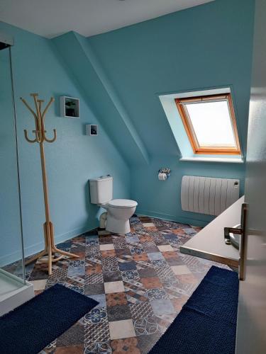 La salle de bains bleue est pourvue de toilettes et d'une fenêtre. dans l'établissement LES HAUTS VENTS, à Saint-Pol-de-Léon