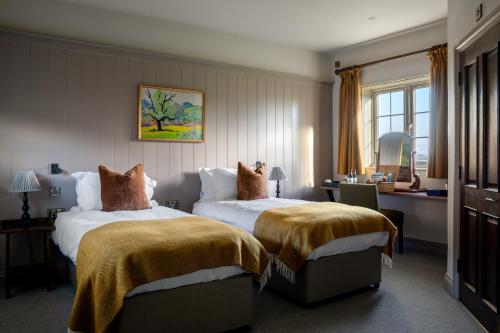 a hotel room with two beds and a desk at Bedford Arms Hotel in Rickmansworth