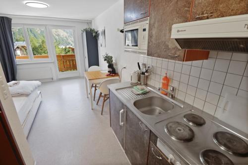 eine kleine Küche mit einem Waschbecken und einem Tisch in der Unterkunft Studio charmant avec vue imprenable in Saas-Fee