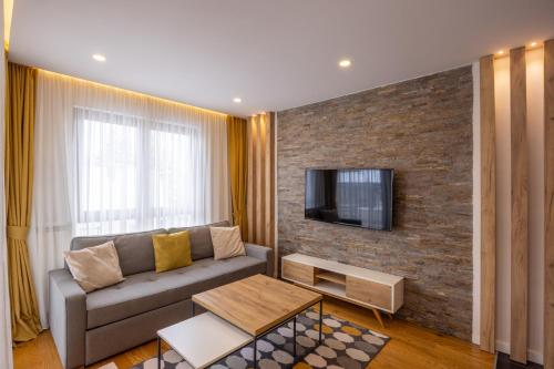 a living room with a couch and a tv on a brick wall at Vip Casa Club Zlatibor in Zlatibor