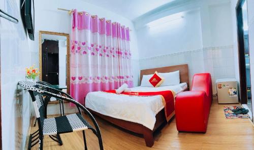 um quarto com uma cama e uma cadeira vermelha em Trung Bảo Hotel em Ho Chi Minh