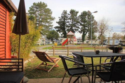 eine Terrasse mit einem Tisch und Stühlen sowie einem Spielplatz in der Unterkunft appartement confort 5 personnes in Grandson