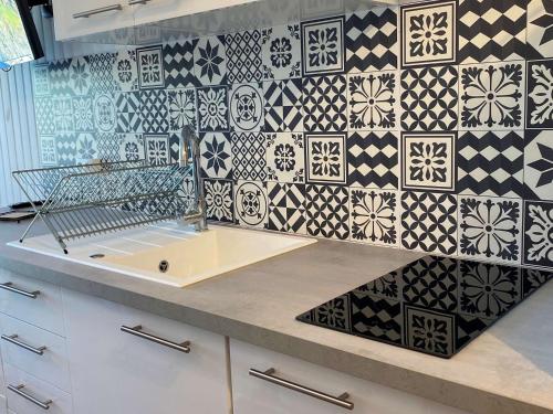 - une cuisine avec du carrelage noir et blanc sur le mur dans l'établissement Studio rénové avec balcon, proche parc, WiFi, lave-linge, Balaruc-les-Bains - FR-1-553-233, à Balaruc-les-Bains
