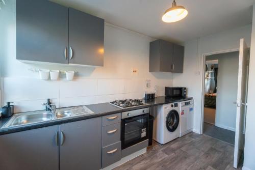 a kitchen with a sink and a washing machine at Cosy Flat 10 mins to Central London sleeps 5 in London