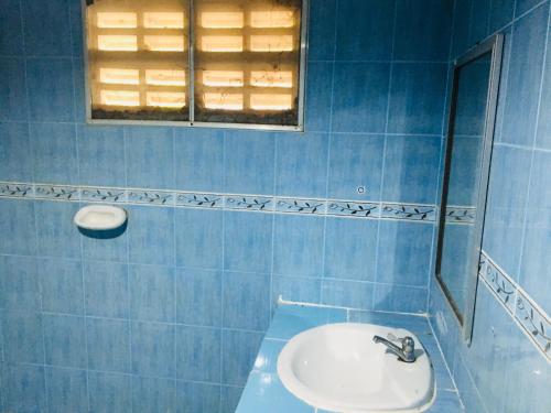 La salle de bains est pourvue de carrelage bleu, d'un lavabo et d'une fenêtre. dans l'établissement ลุงยอด เกสต์เฮ้าส์, à Ban Tha Ling Lom
