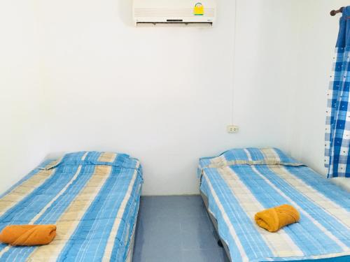 duas camas sentadas uma ao lado da outra num quarto em ลุงยอด เกสต์เฮ้าส์ em Ban Tha Ling Lom