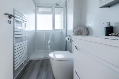 a white bathroom with a toilet and a shower at 19 Undercliffe in Felixstowe