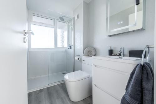 a white bathroom with a toilet and a sink at 19 Undercliffe in Felixstowe