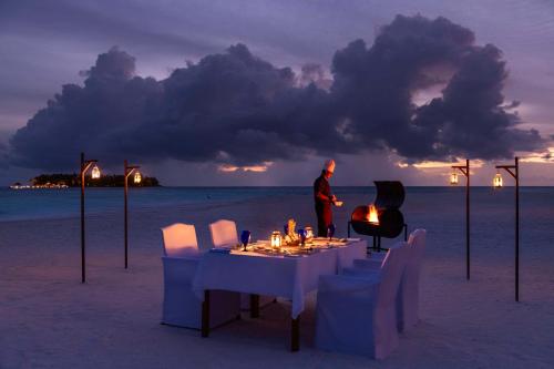 a man standing on the beach with a table and a grill at Banyan Tree Vabbinfaru in Male City