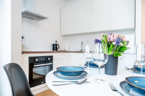 a white kitchen with a table with plates and wine glasses at Apartament w Redłowie - Legionów in Gdynia