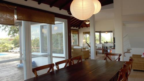 布希奧斯的住宿－AMOUR casa completa con vista de lujo，一间带木桌和大窗户的用餐室