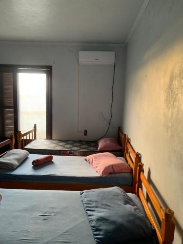 three beds in a room with a window at Hostel 858 in Pelotas
