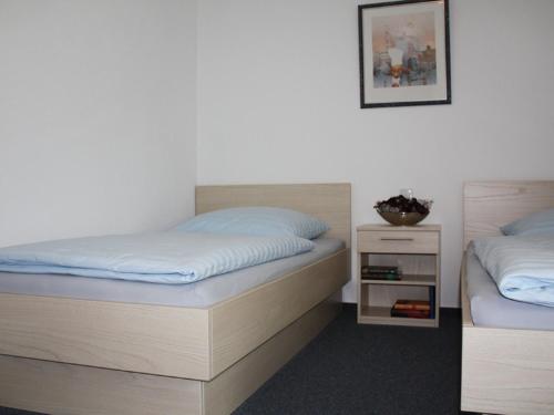 a bedroom with two beds and a night stand at Pension Stadler in Obertraubling