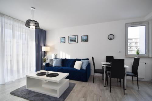 een woonkamer met een blauwe bank en een tafel bij RentPlanet - Apartament Biały Dom in Kołobrzeg