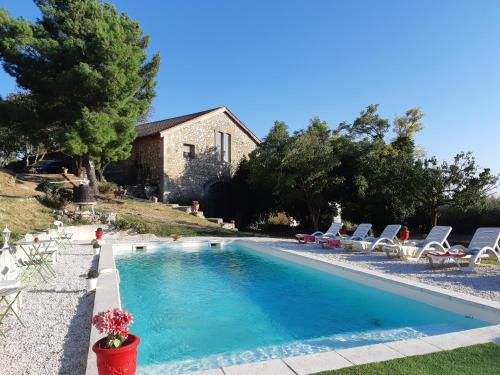 a swimming pool with chairs and a house at Chez Géraldine in Montels