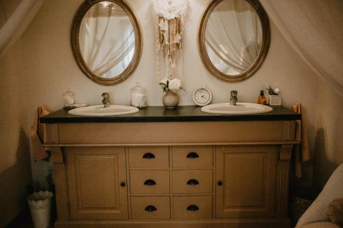 a bathroom with two sinks and two mirrors at Chez Géraldine in Montels