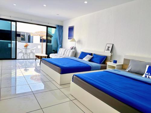 2 camas en una habitación de hotel con sábanas azules en Mona Lisa pool villa, en Pattaya South