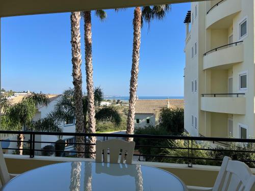 een balkon met palmbomen en een tafel en stoelen bij Apart com vista mar a 2min praia in Lagos