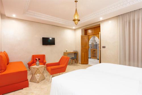 uma sala de estar com mobiliário laranja e uma televisão em Riad Atlas Palace Marrakech em Marraquexe