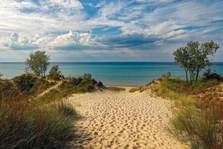 a sandy path leading to the ocean on a beach at Spacious upstairs 1bed- Walking distance to Beach outlet mall in Michigan City