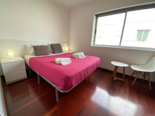 um quarto com uma cama com um cobertor rosa em Luz's Retreat Apartment em Ponta Delgada