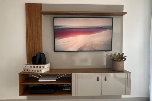 a living room with a television on a wall at BlueCoast 205 Apartment in Rio das Ostras
