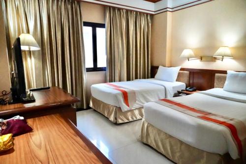 a hotel room with two beds and a television at Kosa Hotel & Wellness Center in Khon Kaen