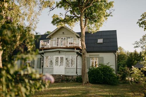 a house with a deck on the front of it at Jūras māja Ausekļi in Kaltene
