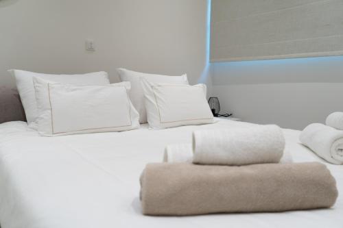 a white bed with white pillows and a chair at Beachfront Luxury Villa Glory in Ayia Napa