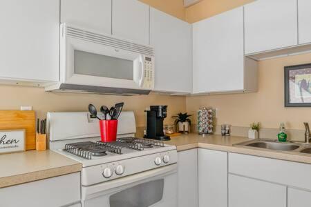 a white kitchen with a stove and a microwave at Studio w King Bed Walking distance to Beach & Shops in Michigan City