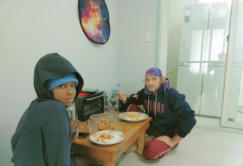 two people sitting at a table eating food at Subhanallah guest house in Yangsan