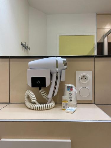 a white hair dryer on a counter in a bathroom at Hôtel Mélodie in Bellignat